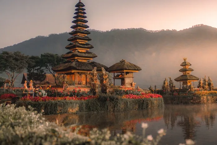 A Balinese temple with tiered roofs beside a lake at dawn