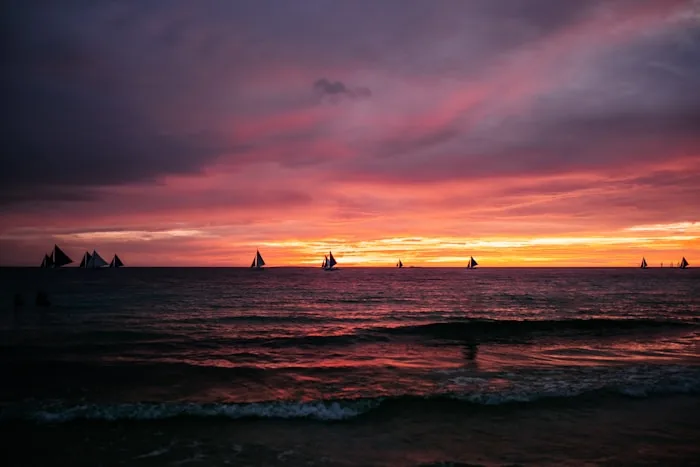 Sailboats silhouetted against a sunset off Boracay