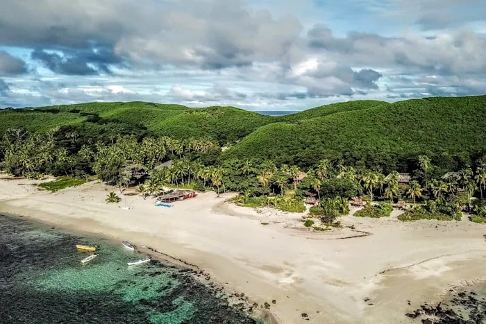 Aerial view of a beach and forested hills on the Fijian coast