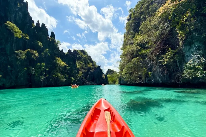 Kayaking on turquoise water between limestone cliffs in Palawan