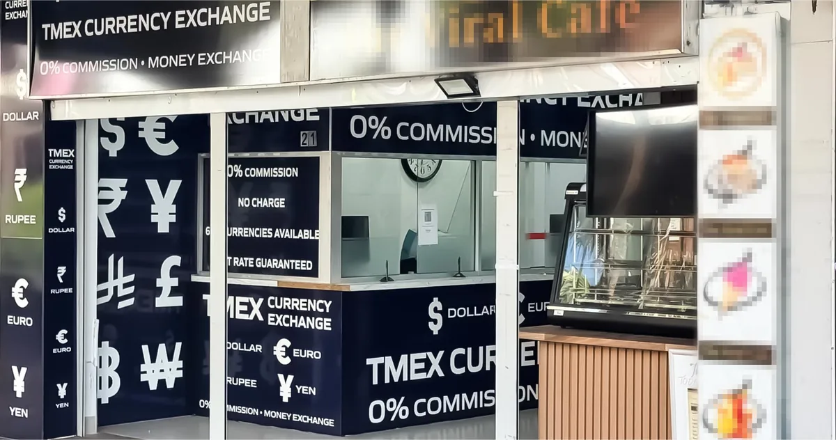 The TMEX Currency Exchange service window on Auburn Road, Auburn, seen from the footpath, with world currency symbols and 0% commission signage across the shopfront.